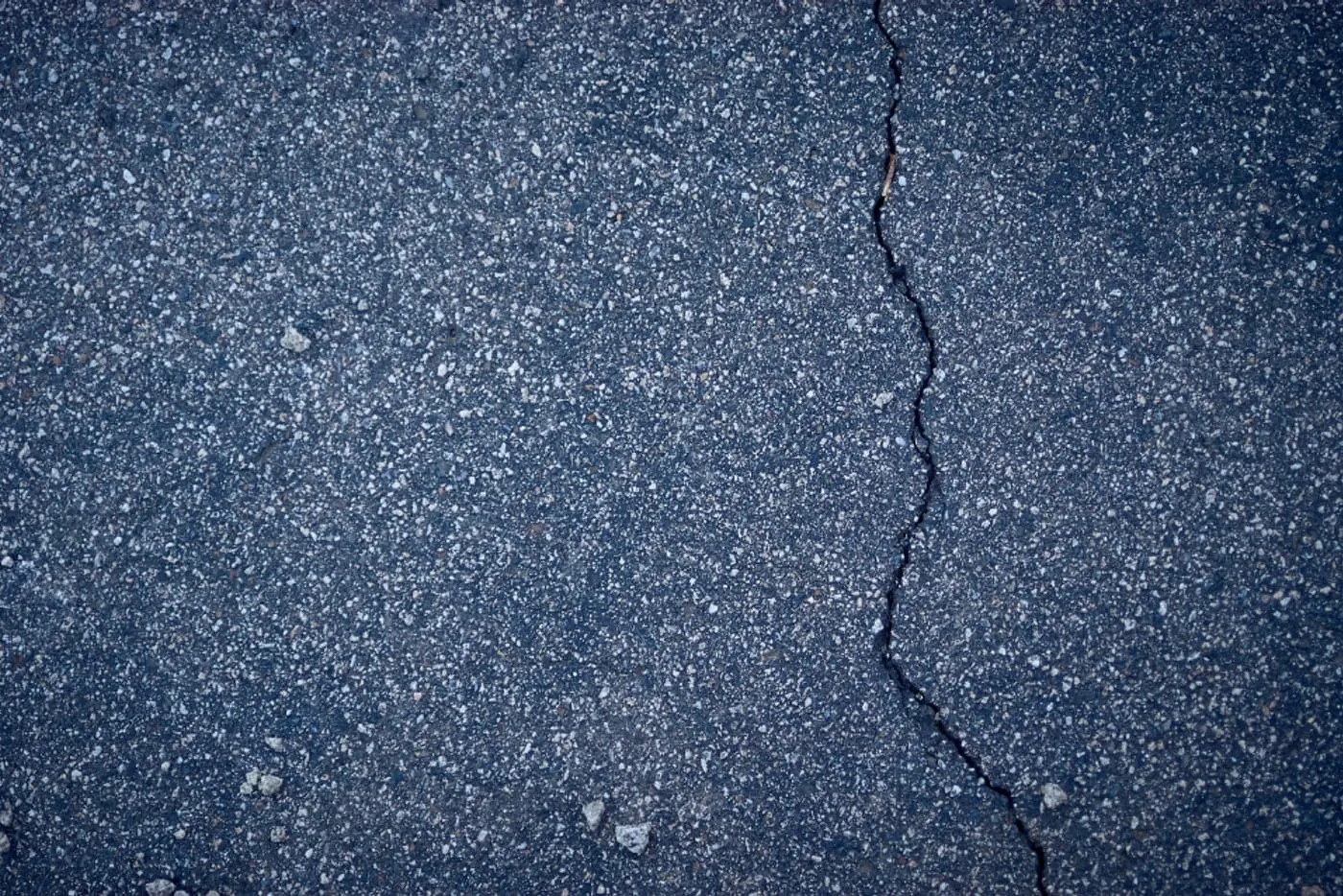 Sutrūkinėjusi betoninė danga iš arti su matomu įtrūkiu